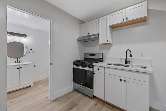 kitchen with white cabinets, gas range, light wood-type flooring, and sink