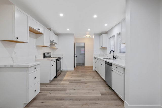 kitchen with sink, white cabinets, light hardwood / wood-style floors, and appliances with stainless steel finishes