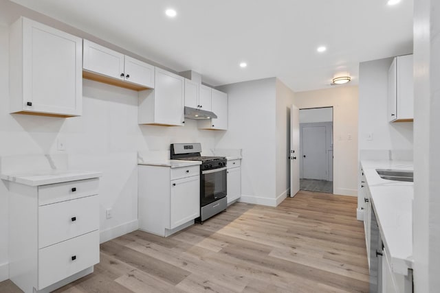 kitchen featuring white cabinets, stainless steel gas range oven, and light hardwood / wood-style flooring