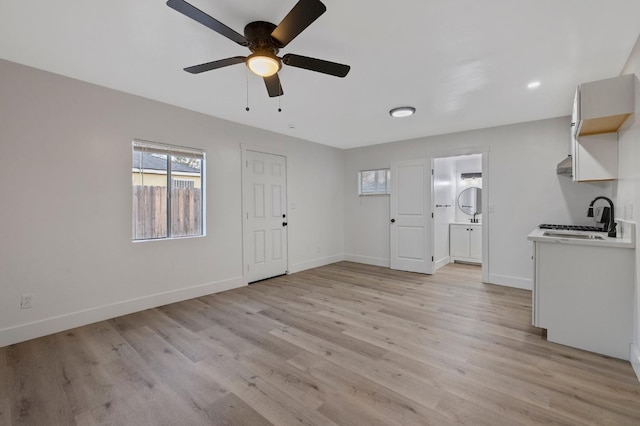 unfurnished living room featuring ceiling fan, light wood-type flooring, and sink