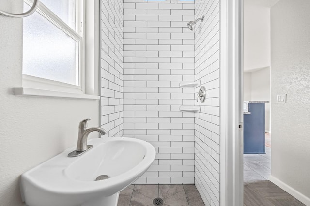 bathroom with tiled shower and sink