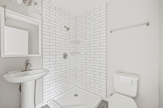 bathroom featuring tiled shower and toilet