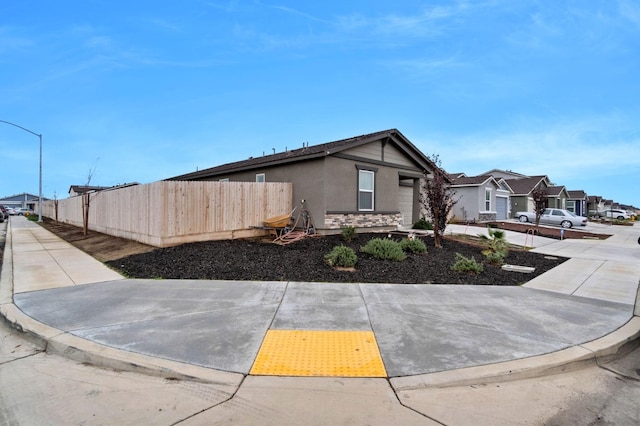 view of home's exterior featuring fence, a residential view, stone siding, and stucco siding