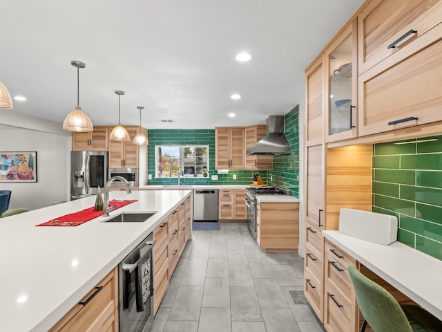 kitchen featuring sink, stainless steel appliances, wall chimney range hood, tasteful backsplash, and pendant lighting