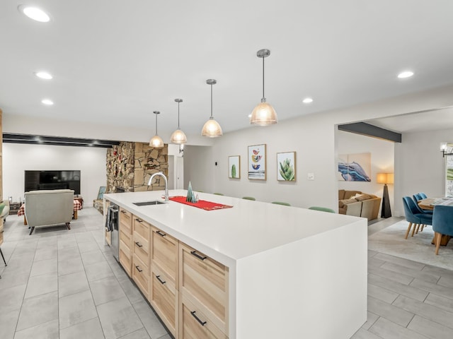 kitchen with a kitchen island with sink, sink, light tile patterned floors, light brown cabinetry, and decorative light fixtures