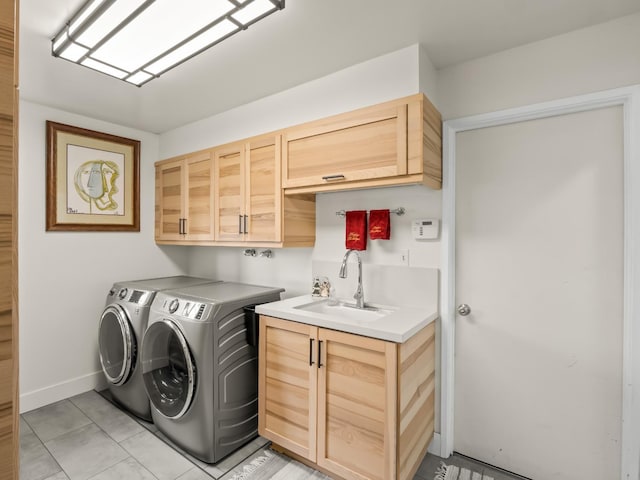 clothes washing area with washer and clothes dryer, cabinets, light tile patterned floors, and sink