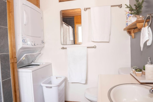 bathroom featuring curtained shower, sink, stacked washer and clothes dryer, and toilet