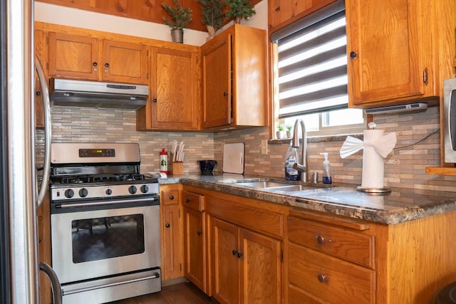 42135 Hanging Branch Rd, Shaver Lake, CA 93664 - kitchen featuring appliances with stainless steel finishes, under cabinet range hood, decorative backsplash, brown cabinets, and dark countertops