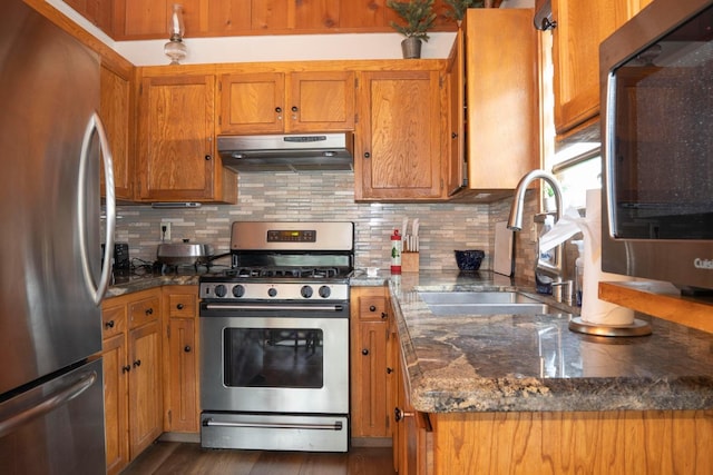 42135 Hanging Branch Rd, Shaver Lake, CA 93664 - kitchen with appliances with stainless steel finishes, exhaust hood, brown cabinets, tasteful backsplash, and dark wood-type flooring