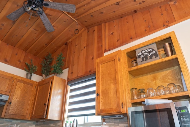 kitchen featuring ceiling fan, wood walls, and vaulted ceiling