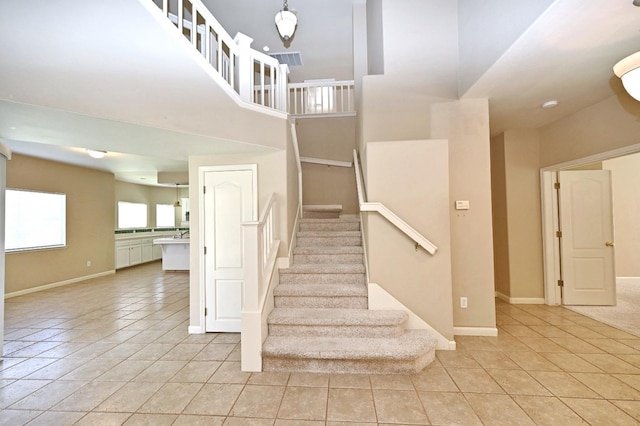 stairs with a high ceiling and tile patterned floors