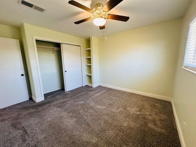975 N Princeton Ave, Coalinga, CA 93210 - unfurnished bedroom featuring ceiling fan, a closet, and dark colored carpet
