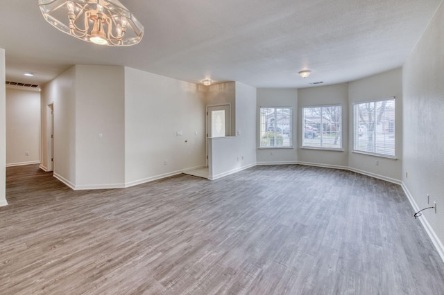 empty room with hardwood / wood-style floors and an inviting chandelier