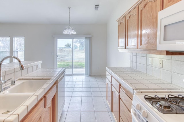 kitchen with light brown cabinetry, white appliances, sink, tile countertops, and a chandelier