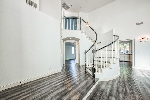 staircase with hardwood / wood-style floors and a high ceiling