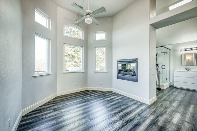 empty room featuring a high ceiling, dark wood-type flooring, electric panel, and ceiling fan