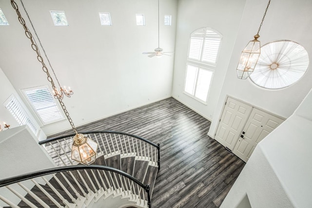 entryway with an inviting chandelier, a towering ceiling, and dark wood-type flooring