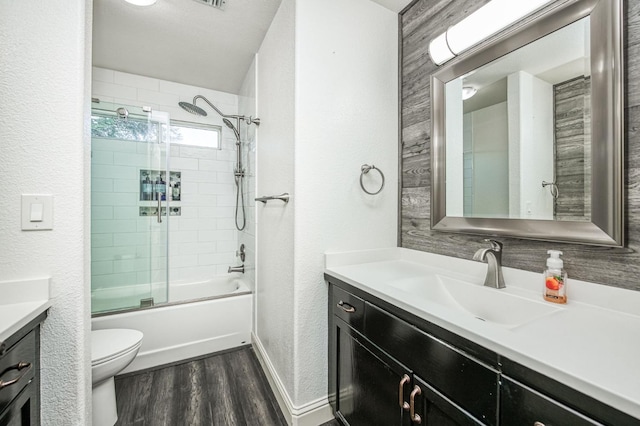 full bathroom with vanity, hardwood / wood-style floors, shower / bath combination with glass door, and toilet