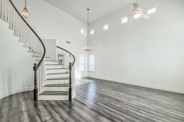 interior space featuring hardwood / wood-style flooring, ceiling fan with notable chandelier, and a high ceiling