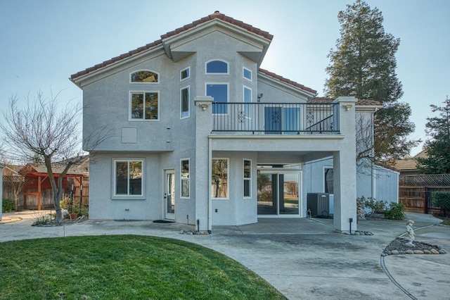 rear view of house with a balcony, a yard, and a patio area