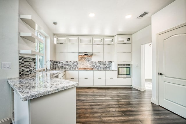 kitchen featuring sink, oven, kitchen peninsula, light stone countertops, and white cabinets