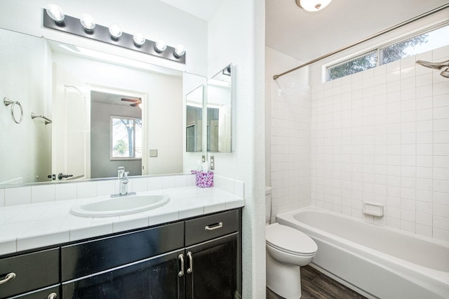 full bathroom with vanity, hardwood / wood-style flooring, tiled shower / bath combo, and toilet