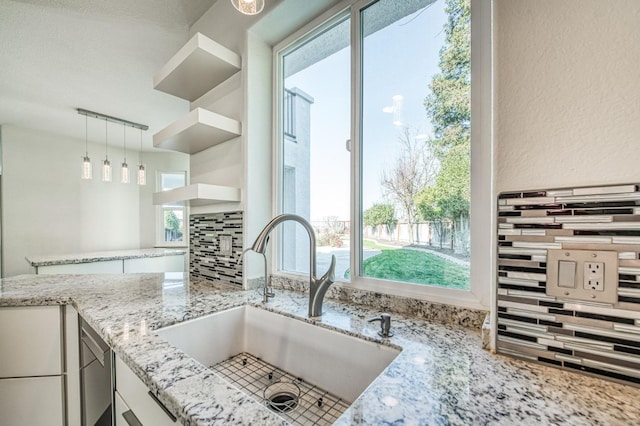 kitchen featuring decorative light fixtures, tasteful backsplash, sink, white cabinets, and track lighting