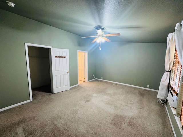 unfurnished bedroom featuring ceiling fan, carpet, a spacious closet, and lofted ceiling