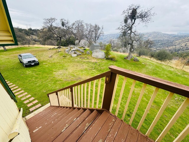 wooden deck with a mountain view and a yard