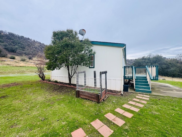 view of home's exterior featuring a deck with mountain view and a lawn