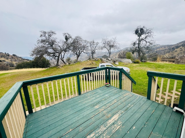 wooden deck featuring a mountain view and a yard