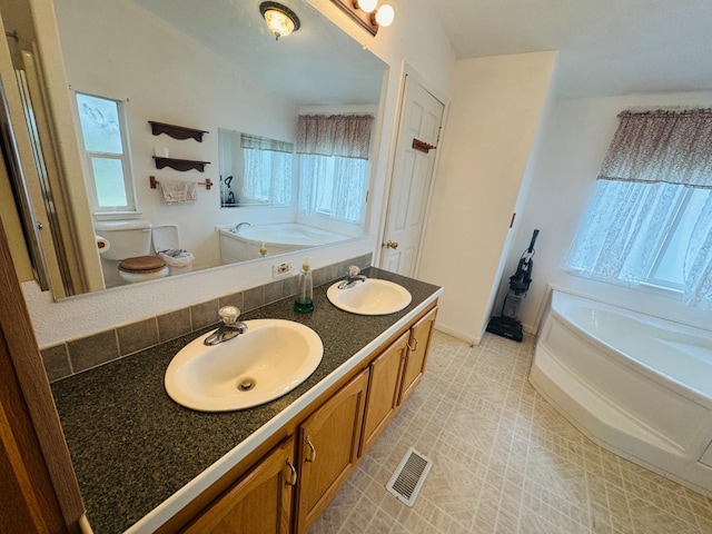 bathroom with a bathing tub, tile patterned floors, lofted ceiling, toilet, and vanity