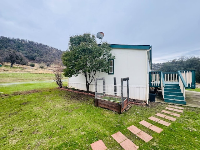 view of side of home featuring a deck with mountain view and a lawn