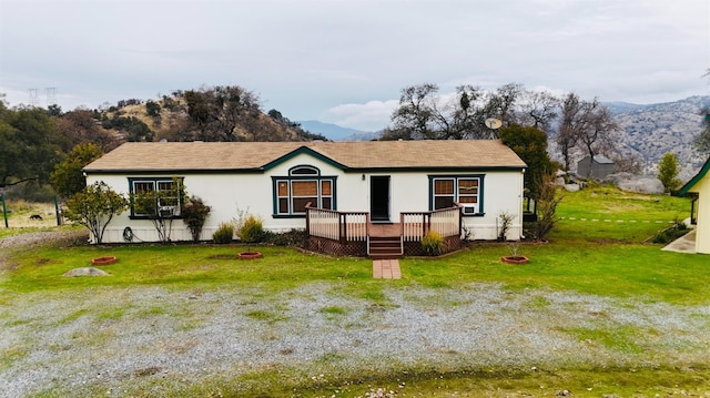 view of front of property with a front yard, a fire pit, and a deck with mountain view