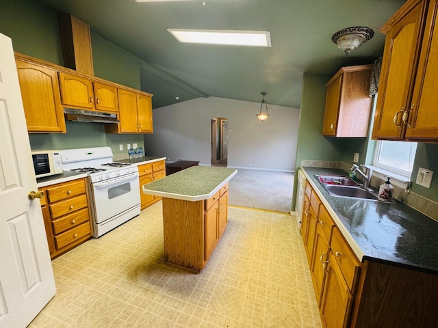 kitchen with lofted ceiling, white appliances, sink, hanging light fixtures, and a kitchen island