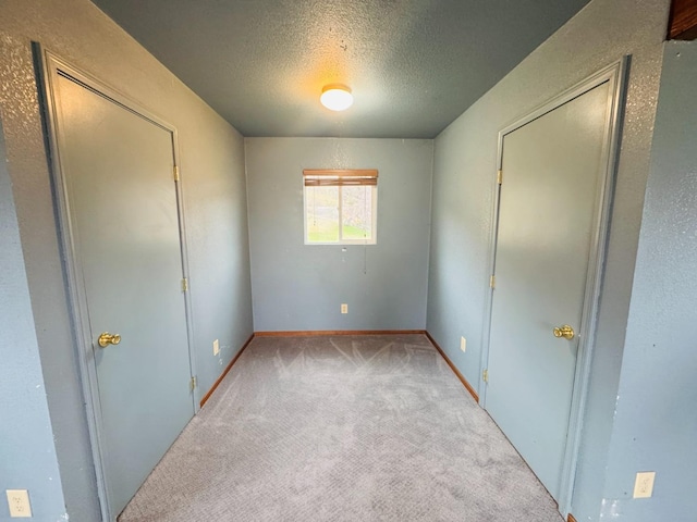 unfurnished bedroom with a textured ceiling, light carpet, and a closet