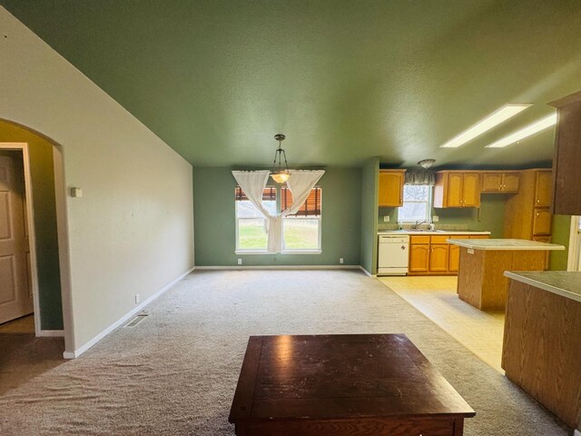 kitchen with white dishwasher, light colored carpet, sink, decorative light fixtures, and a center island