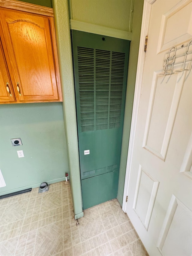 laundry area with electric dryer hookup and cabinets