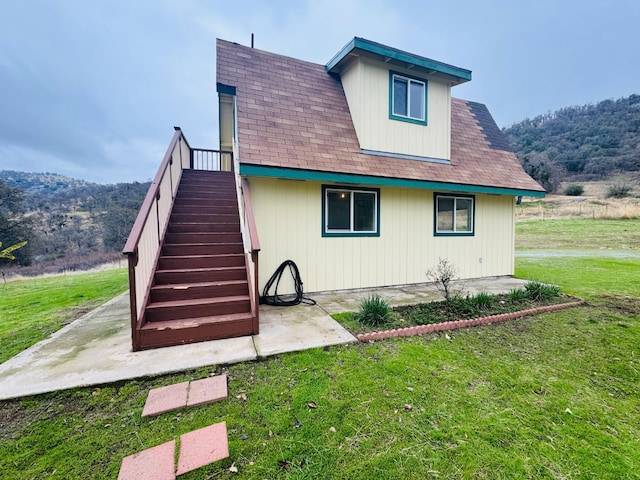 rear view of house with a lawn, a patio area, and a mountain view