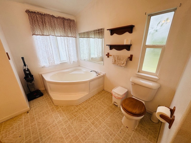 bathroom featuring tile patterned flooring, plenty of natural light, toilet, and a tub to relax in