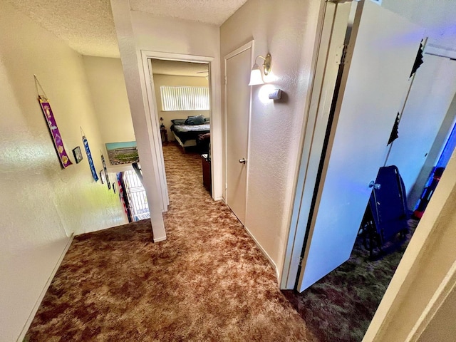 corridor featuring a textured ceiling and carpet floors