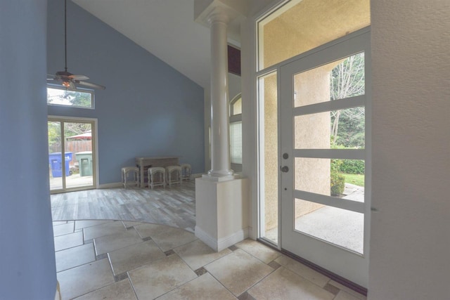 foyer entrance featuring high vaulted ceiling, decorative columns, light hardwood / wood-style flooring, and ceiling fan