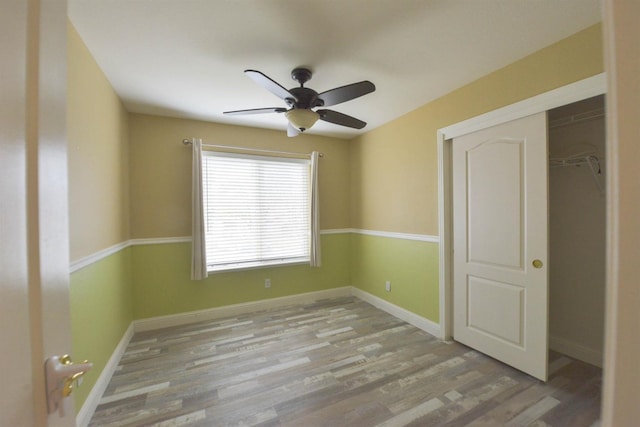 unfurnished bedroom with ceiling fan, light wood-type flooring, and a closet