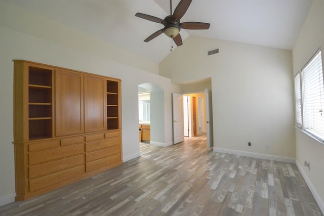 unfurnished bedroom featuring ensuite bathroom, ceiling fan, wood-type flooring, and high vaulted ceiling