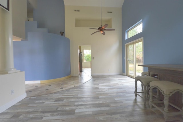 living room with light wood-type flooring, high vaulted ceiling, a wealth of natural light, and ornate columns