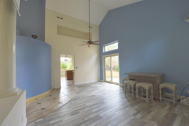 living room featuring ceiling fan, ornate columns, high vaulted ceiling, and light hardwood / wood-style flooring