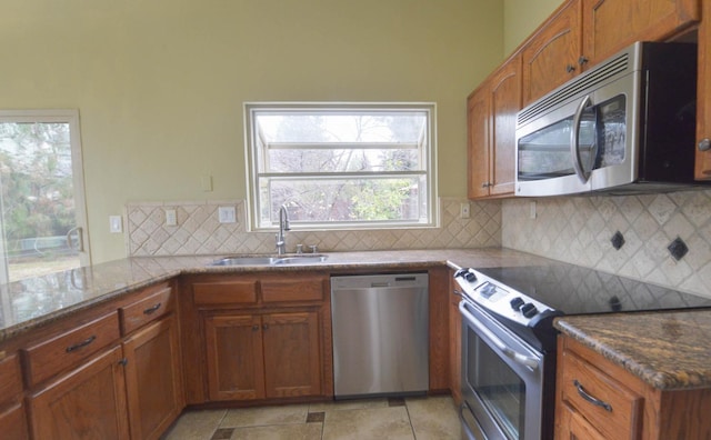 kitchen featuring sink, decorative backsplash, stone countertops, kitchen peninsula, and stainless steel appliances