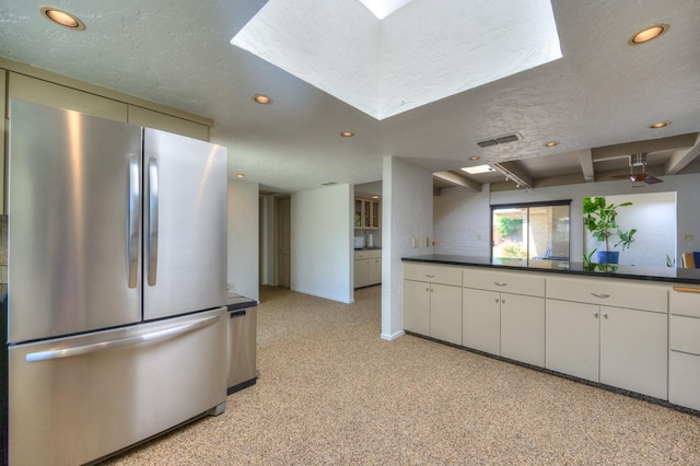 kitchen featuring white cabinets, a textured ceiling, and stainless steel refrigerator