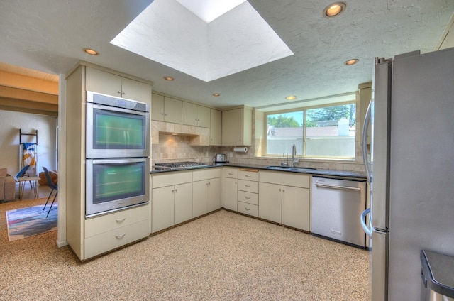 kitchen featuring a textured ceiling, sink, appliances with stainless steel finishes, and tasteful backsplash