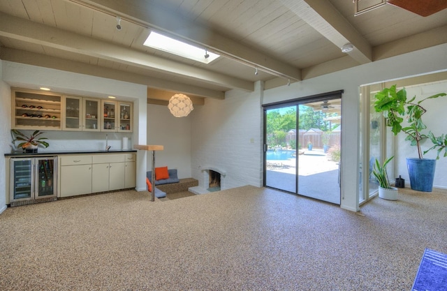 interior space featuring beamed ceiling, white cabinets, and beverage cooler